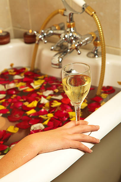 Relaxing in tub of rose petals with glass of wine